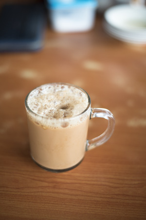 a glass of tea with milk on a table at mamak restaurant.famous or popular drink in malaysia.Malaysian favorite drink known as Teh Tarik.signature menu at mamak stall,cafe,restaurant or bistroの写真素材