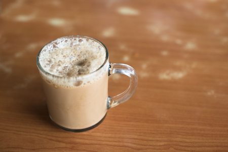 a glass of tea with milk on a table at mamak restaurant.famous or popular drink in malaysia.Malaysian favorite drink known as Teh Tarik.signature menu at mamak stall,cafe,restaurant or bistroの写真素材