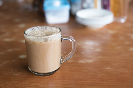 a glass of tea with milk on a table at mamak restaurant.famous or popular drink in malaysia.Malaysian favorite drink known as Teh Tarik.signature menu at mamak stall,cafe,restaurant or bistroの写真素材
