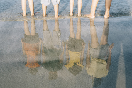 reflection of kids standing at the beach in the evening.travel and family concept,friendship and togetherness conceptの写真素材