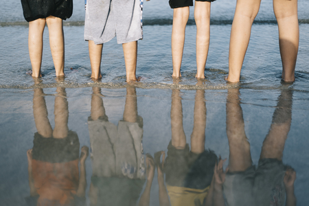 reflection of kids standing at the beach in the evening.travel and family concept,friendship and togetherness conceptの写真素材