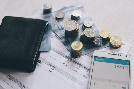 Coins,money,wallet,bills and smartphone on a table. Calculating to pay bills.financial concept and life conceptの写真素材