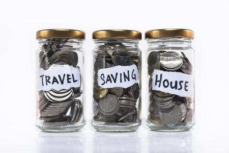 coins in a jar isolated on white background.saving concept. saving for travel,future and home/houseの写真素材