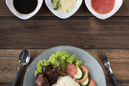 Popular Malaysian dish Nasi Ayam or chicken rice with baked chicken pieces, tomato, cucumber, salad, soup, soy sauce and chili sauce.の写真素材