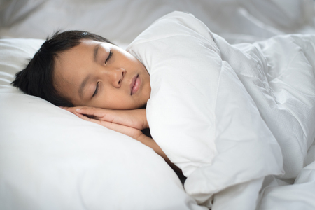 boy sleeping on bed with white sheet and pillow.asian kid fall asleep daydreaming.sleep conceptの写真素材