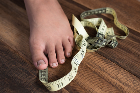 boy measure his feet using measuring tape.growth conceptの写真素材