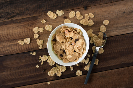 breakfast cereal ( cornflakes ) in a bowl on a wooden table background. healthy eating conceptの写真素材