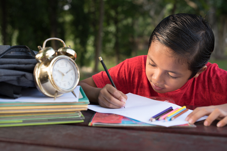 young asian boy having fun drawing at park in the evening sunny day.の写真素材