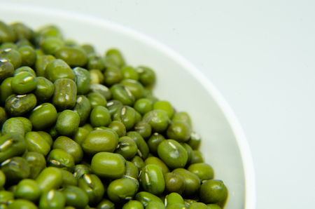 Mung beans in yellow bowl isolated on white background. also known as moong bean, green gram, green bean. its in legume family speciesの写真素材