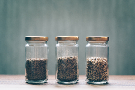 sweet cumin, white cumin and coriander seed in a glass jar on a wooden tableの写真素材