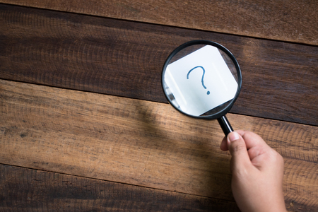 hand holding magnifying glass focusing on question mark. mystery and search conceptの写真素材