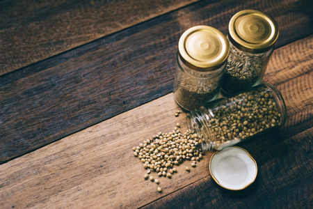 coriander seeds in a glass jar on a wooden tableの写真素材