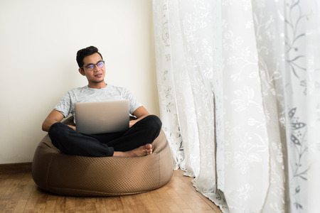asian teen holding a laptop while looking at an empty space.の写真素材