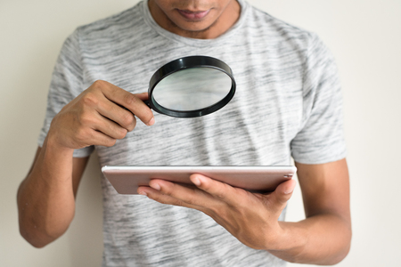 asian teen holding magnifying glass and digital tablet. search online conceptの写真素材