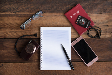 notebook, passport, camera, compass and smarphone on a wooden table. travel conceptの写真素材