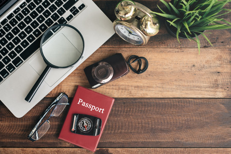 notebook, laptop, smartphone, compass, passport, clock and camera on wooden table background. travel conceptの写真素材
