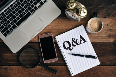 laptop, clock, phone, magnifying glass, coffee and notebook with Q&A word. Questions and answer conceptの写真素材