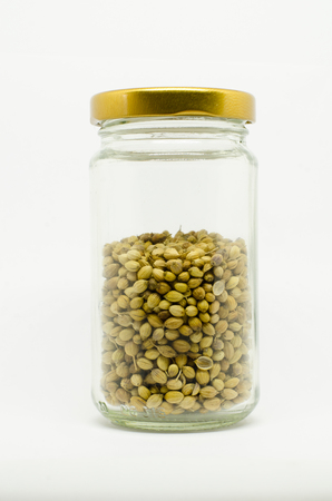 coriander seeds in a jar isolated on white backgroundの写真素材
