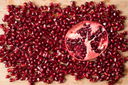 cross section of pomegranate and pomegranate seeds on wooden boardの写真素材