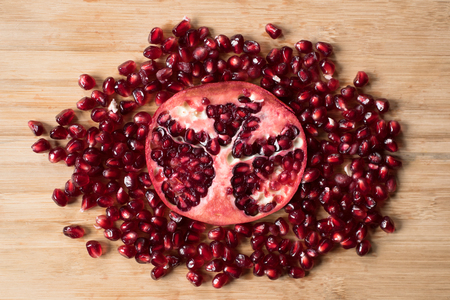 cross section of pomegranate and pomegranate seeds on wooden boardの写真素材