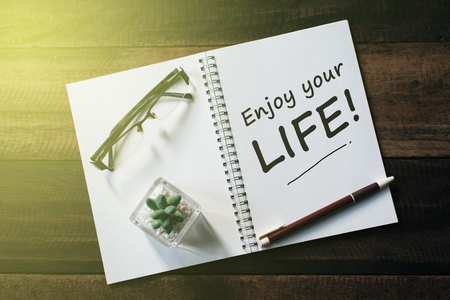 cactus, glasses, pen and notebook with ENJOY YOUR LIFE word on wooden table. lifestyle conceptの写真素材