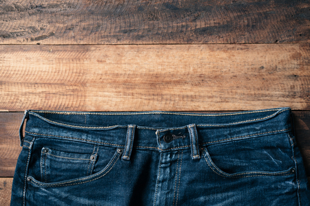 Blue denim jeans on wooden table. Fashion concept with copy spaceの写真素材