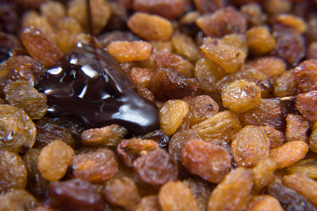 pile of raisins covered with melt chocolate. healthy food conceptの写真素材