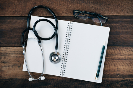 Stethoscope and blank notebook on wooden table background. healthcare and medical conceptの写真素材