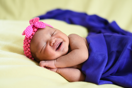 asian newborn baby on yellow background wrapped with blue cloth. life conceptの写真素材