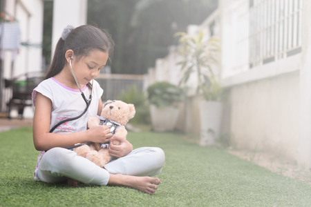 young little asian girl playing pretend to be a doctor. young girl eaxamine her teddy bear with stethoscope. ambition and child healthcare conceptの写真素材