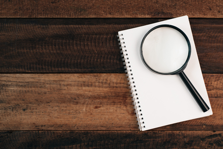magnifying glass on a blank notebook on a wooden table. research conceptの写真素材