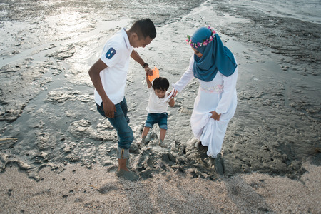 happy asian family wearing casual and playing with mud at the muddy beach located in pantai remis, kuala selangor, selangor, malaysiaの写真素材