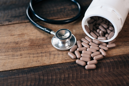 vitamin pills, bottle and stethoscope on a wooden table. health care and medical conceptの写真素材