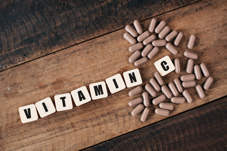 Vitamin C pills on wooden table with alphabet tiles written VITAMIN C. Healthcare and medical conceptの写真素材