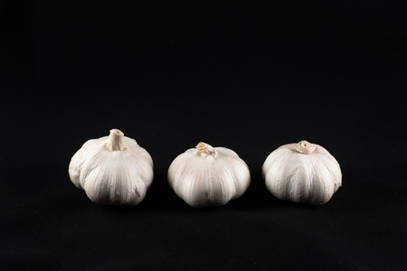 three unpeeled garlic isolated on black background. food ingredients and cooking concept