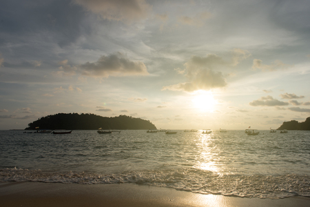 view of a sunset sky and silhouette of floating boats and small island on the beach as foreground located in Pangkor island, perak, malaysiaの写真素材