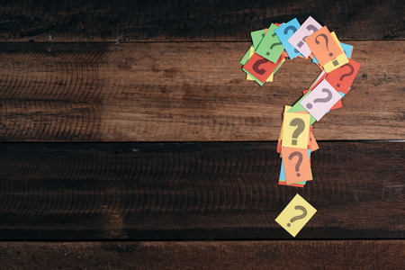 multicolored paper with QUESTION MARK on a wooden table background. questions,mystery and diversity concept. FAQ and Q&A background conceptの写真素材