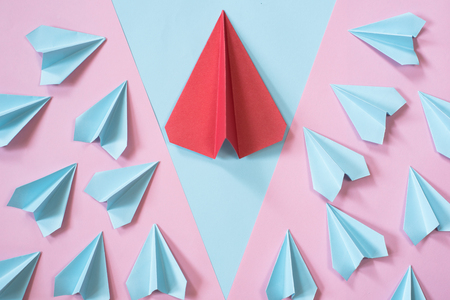 blue paper airplanes surrounding the bigger red paper airplane on pastel pink and blue color background. leadership conceptの写真素材