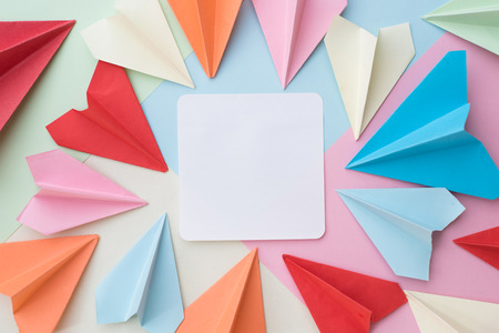 colourful paper airplane and blank white memo paper pad on colorful pastel background....