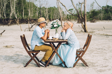 lovely asian couple having a romantic moment of happiness outdoor with picnic table and chair. love and dating concept. horizontal imageの写真素材