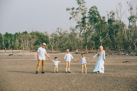 Portrait of an Asian Malaysian family looking very happy outdoors holding hand together. love and family conceptの写真素材