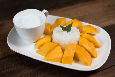 mango sticky rice or Khaoniao mamuang on a wooden table, a traditional thai dessert made with glutinous rice,fresh mango and coconut milkの写真素材