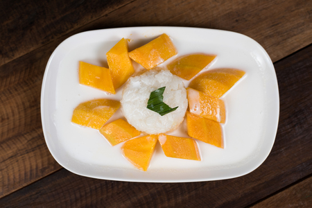 mango sticky rice or Khaoniao mamuang on a wooden table, a traditional thai dessert made with glutinous rice,fresh mango and coconut milkの写真素材