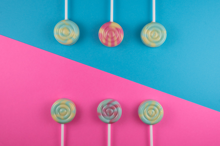 assortment of colorful lollipop on pink and blue colored background. sweet food conceptの写真素材
