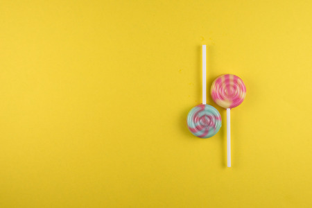 assortment of colorful lollipop over yellow colored background. sweet food conceptの写真素材