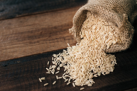 natural unpolished brown rice on wooden table. healthy food and eating concept. selective focusの写真素材
