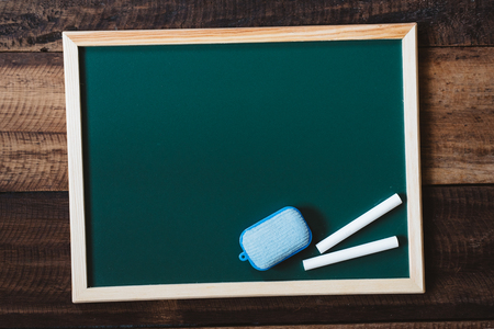 blank chalkboard with duster and white chalk on wooden table. education, school, study and memo conceptの写真素材