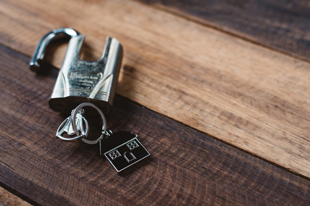 lock, key and house shape key tag on wooden table. house security and privacy conceptの写真素材