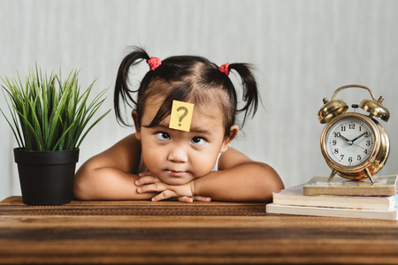 cute and confused lookian asian toddler with question mark on her forehead. concept of child learning education, growth and development.の写真素材