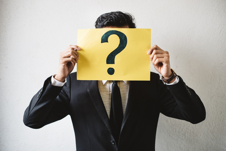 Young adult asian businessman holding yellow signboard paper with QUESTION MARK. Concept of business FAQ and questionsの写真素材